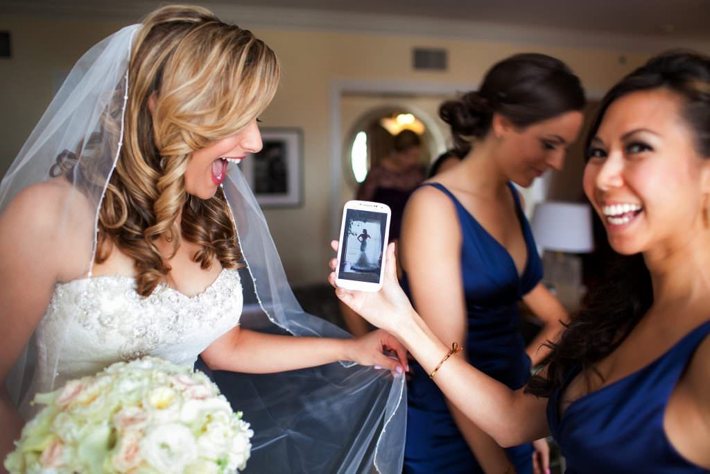 A bride is taking a picture of herself with her bridesmaids