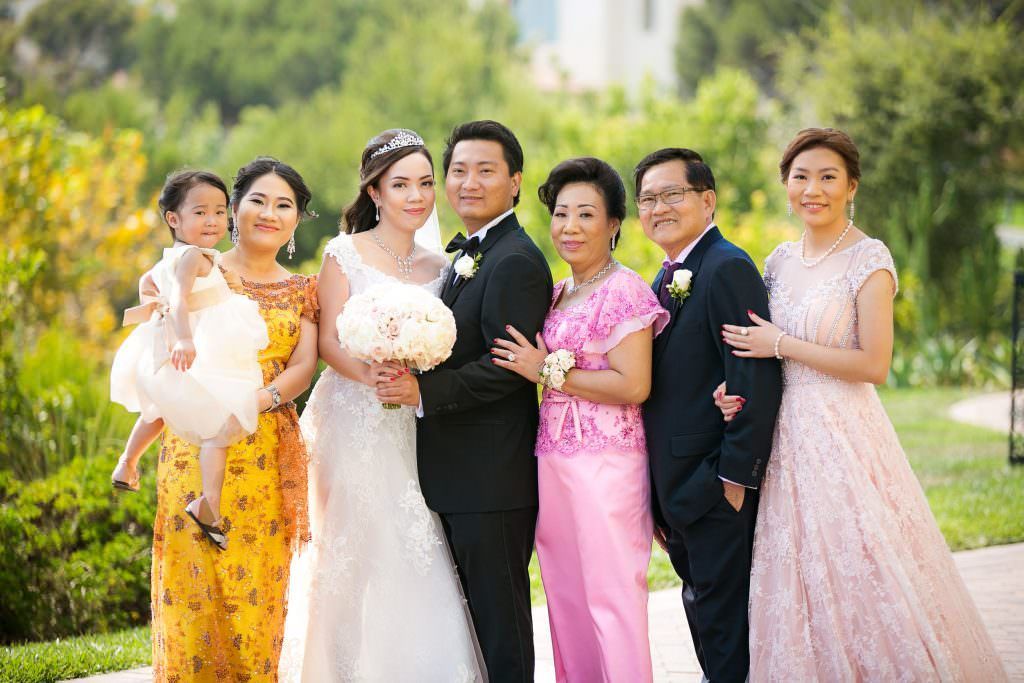 A bride and groom are posing for a picture with their family.