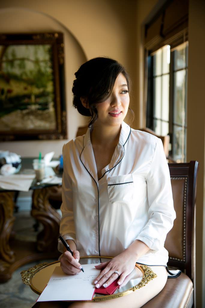 A woman is sitting in a chair writing on a piece of paper.