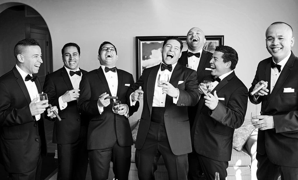 A group of laughing, groomsmen, drinking champagne
