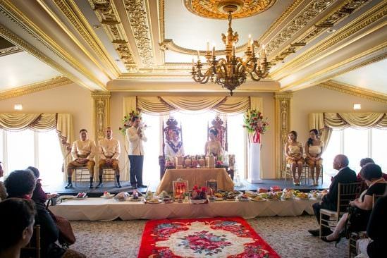 A group of people are sitting in a room watching a Cambodian wedding ceremony.
