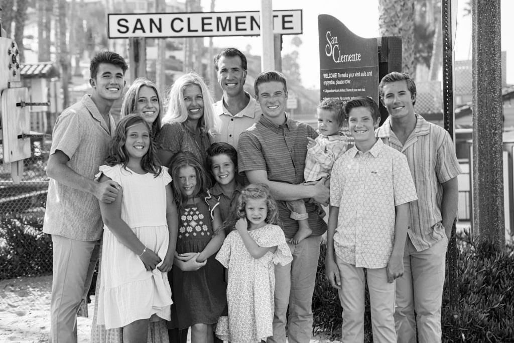 A black and white photo of a family posing in front of a sign that says san clemente