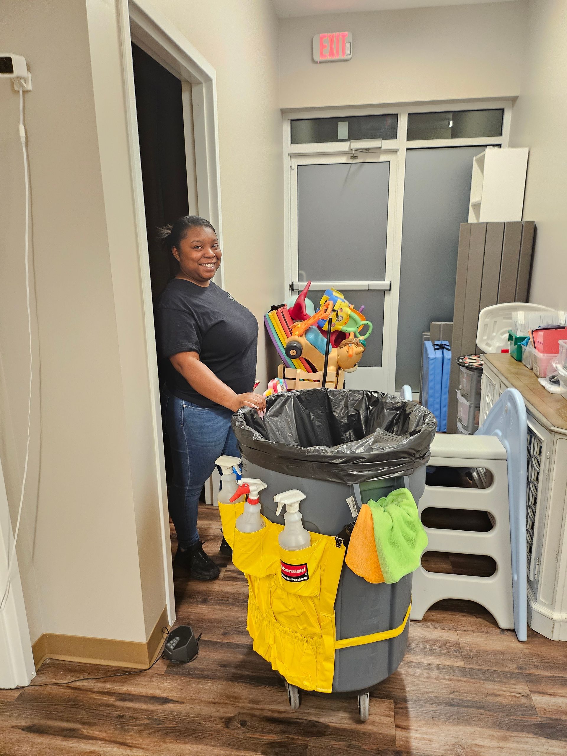 Cleaning cart with yellow buckets, broom, and mop against a glass wall.
