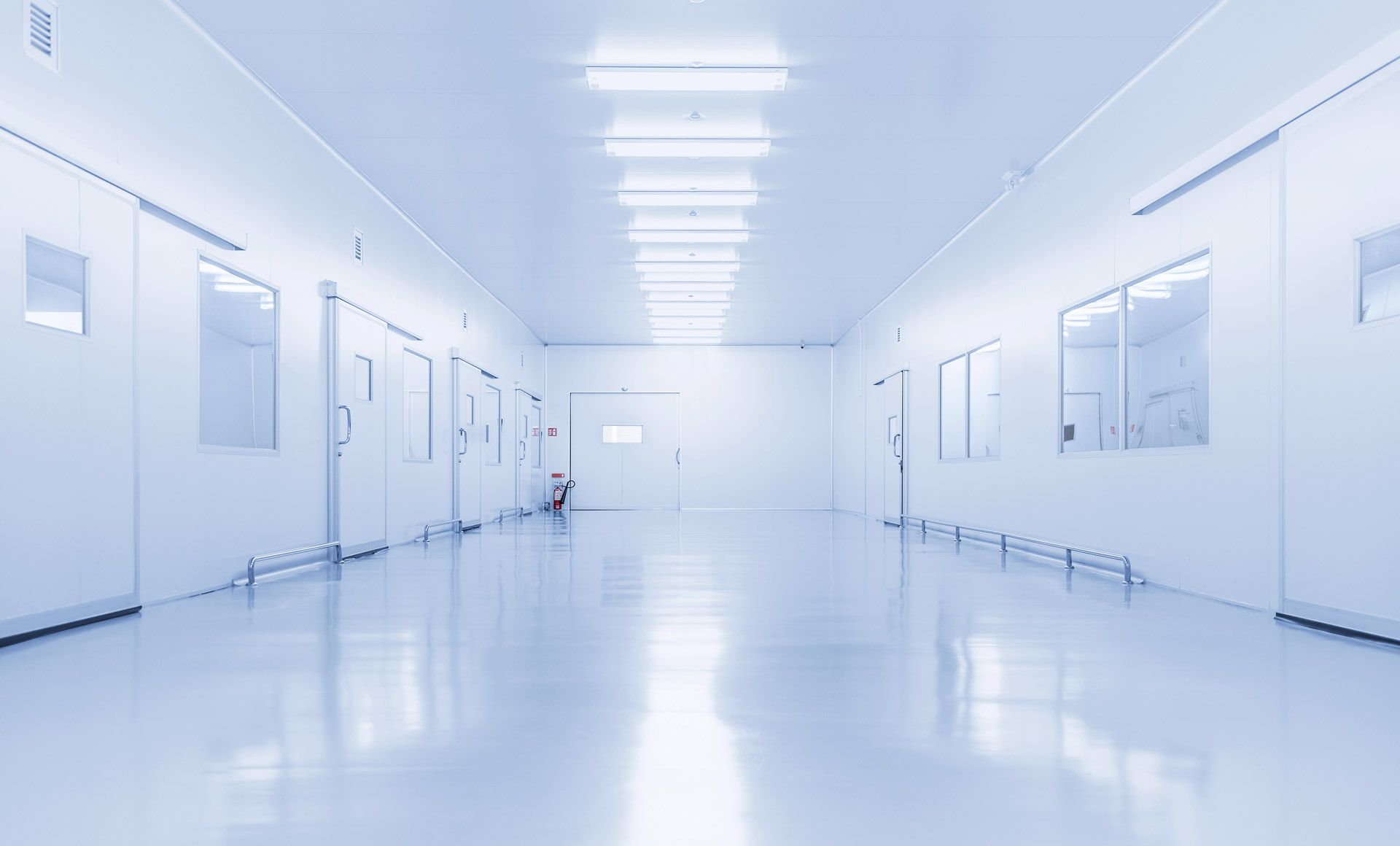 A bright, sterile hallway in a laboratory or industrial facility with white walls, polished floors, and uniform lighting.