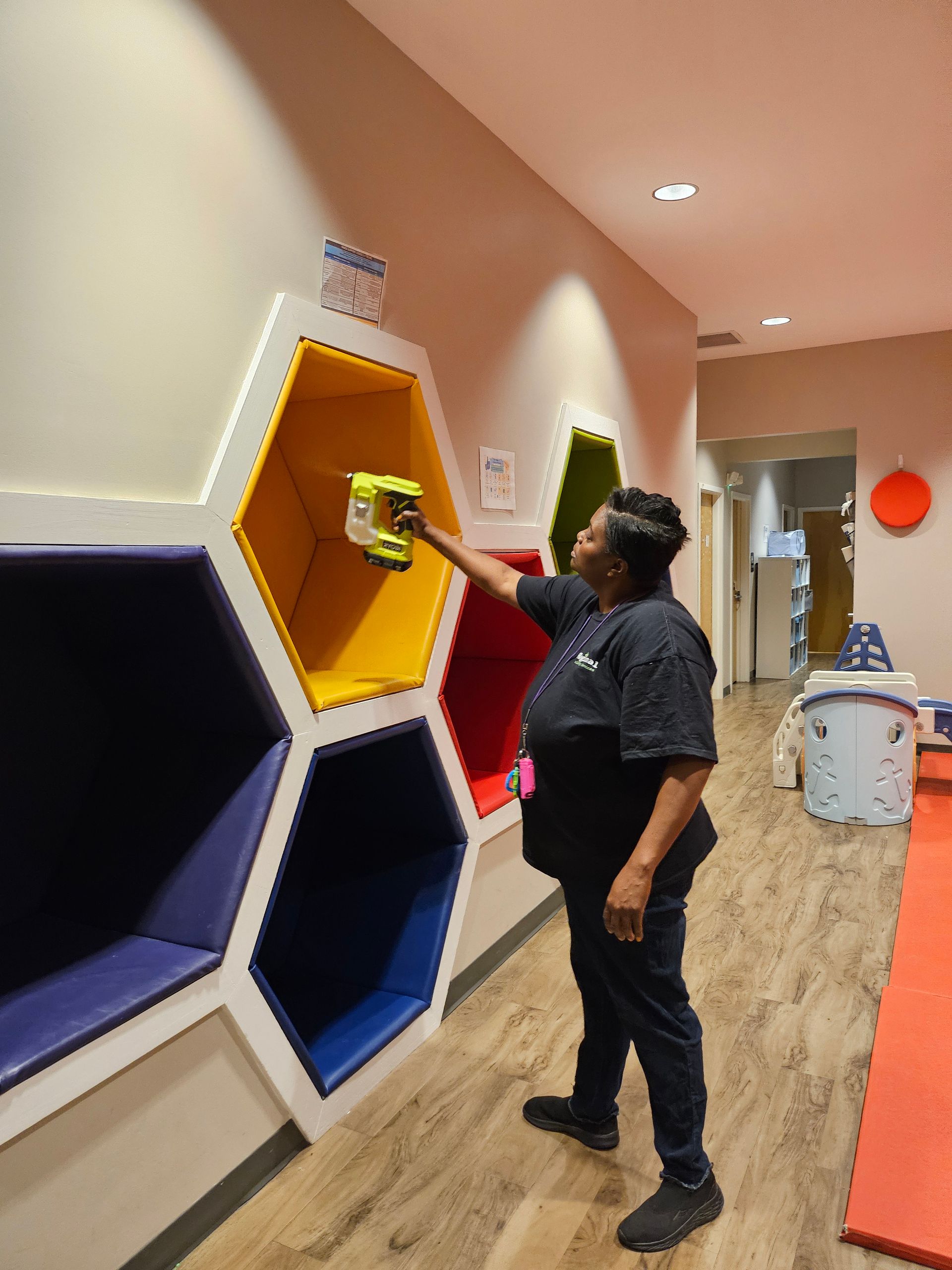 Two people wearing blue aprons and yellow gloves bump fists in a cleaning office.