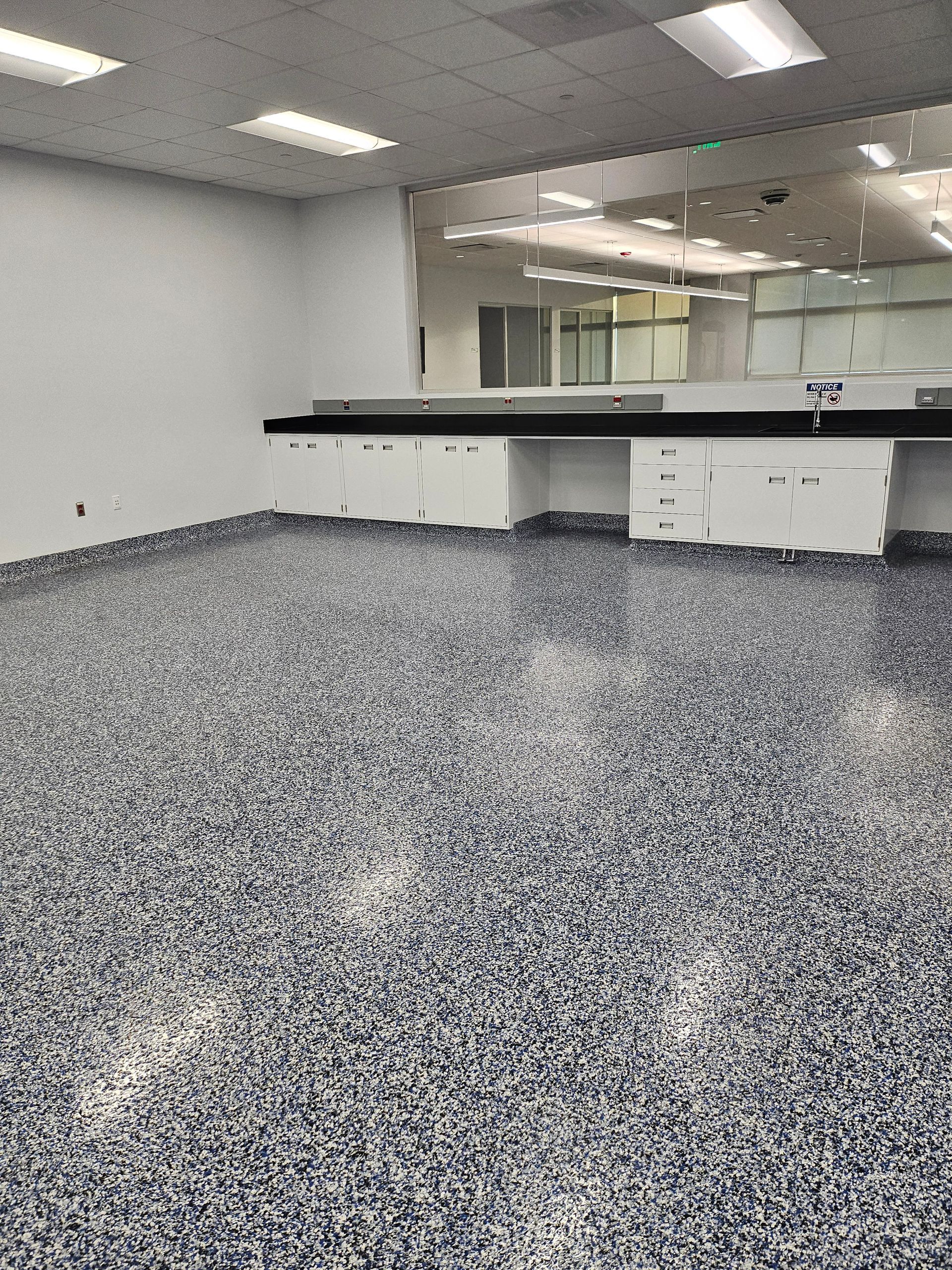 Nurse in blue vest, preparing gloves in hospital room, patient in bed.