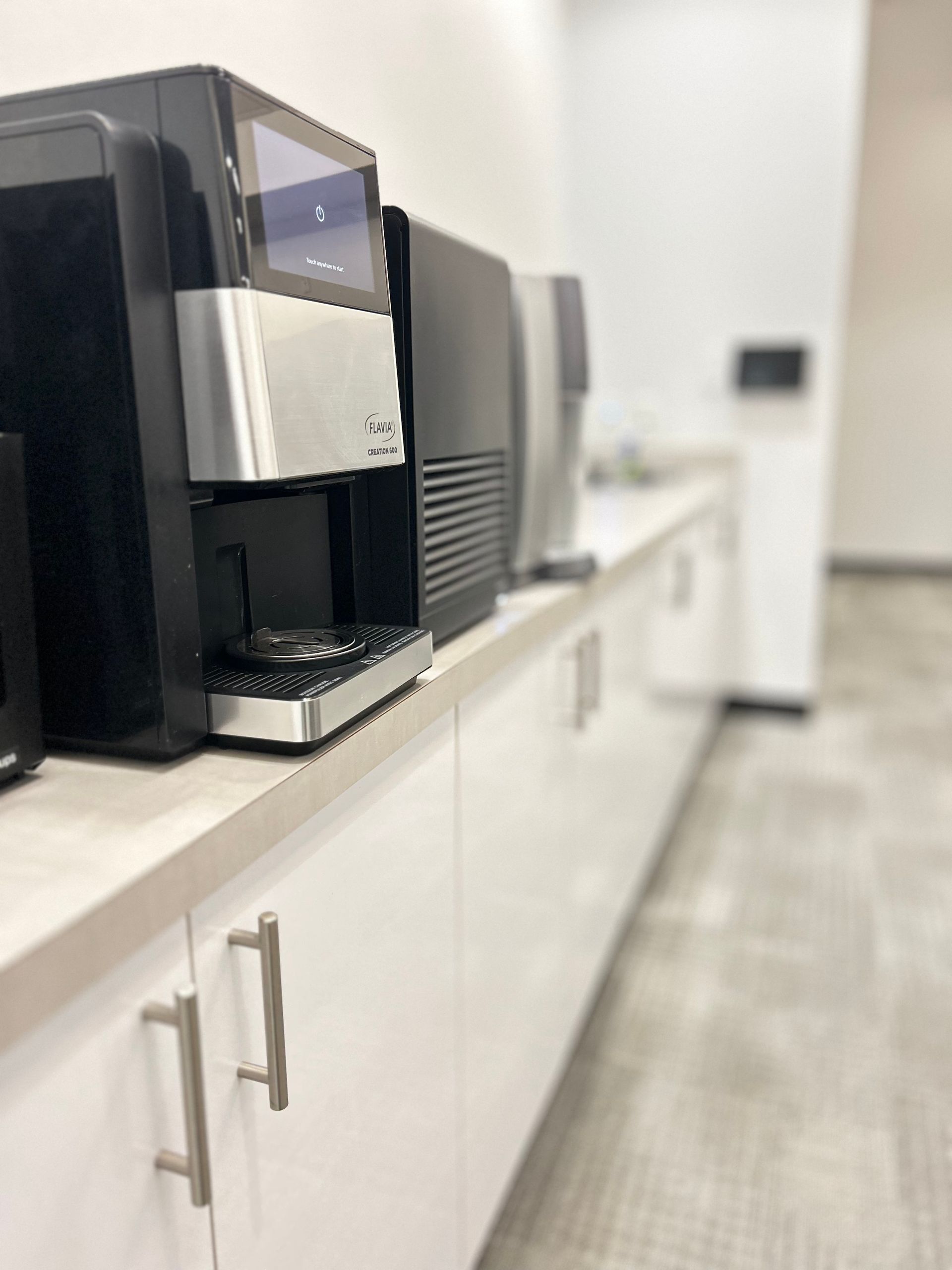 Person mopping a blue floor in a hallway with a blue bucket to the left and doors to either side.