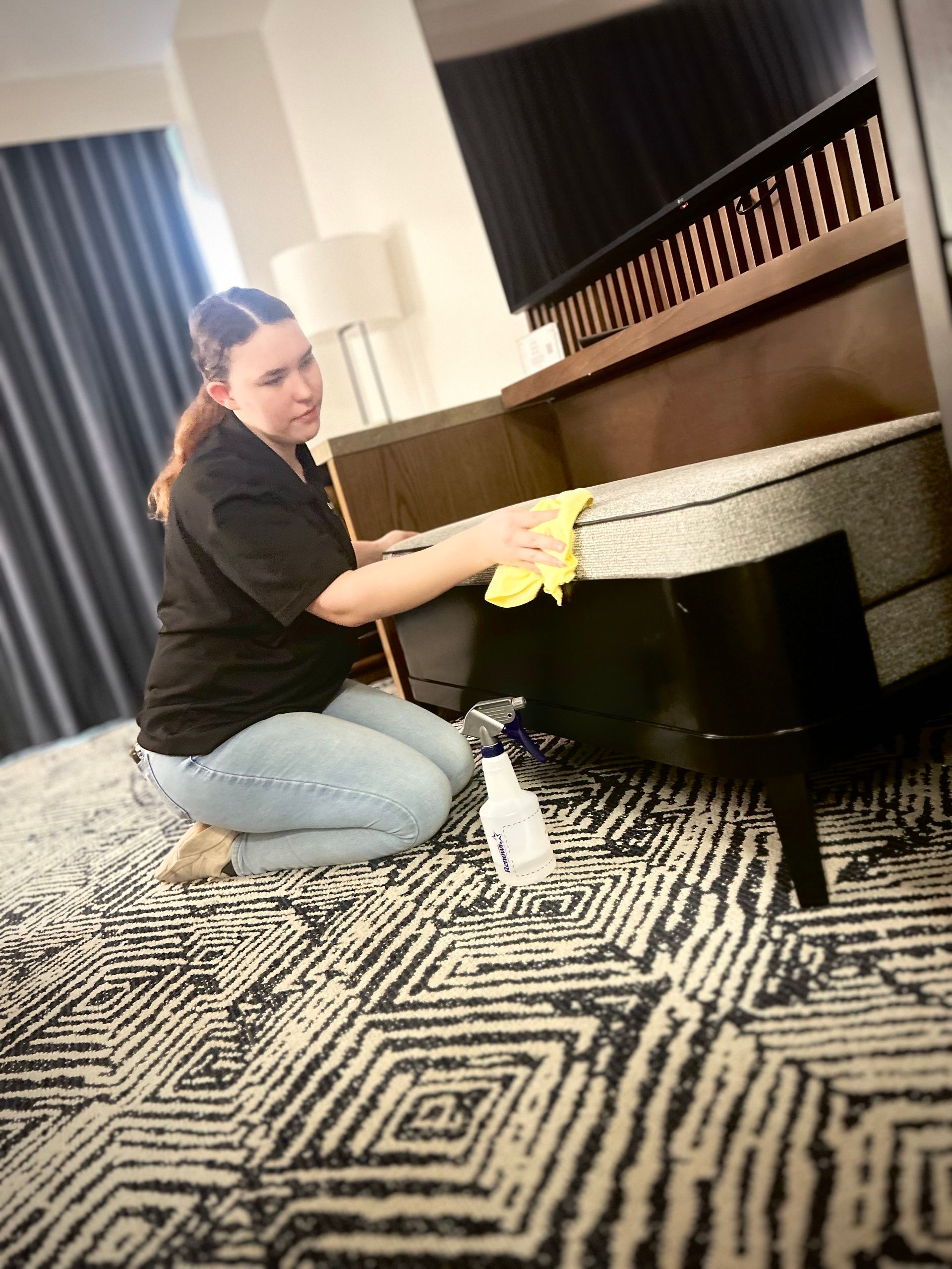 Carpet cleaning machine with water jets and spinning brushes cleaning a light-colored rug.