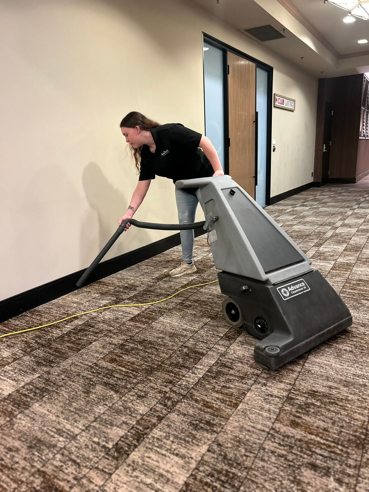 Person cleaning a teal sofa with a vacuum cleaner.