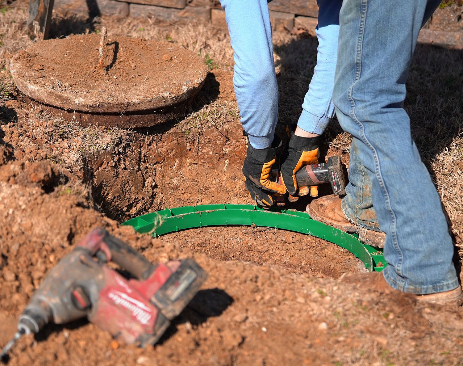 Crew member skillfully installing septic tank risers using a drill