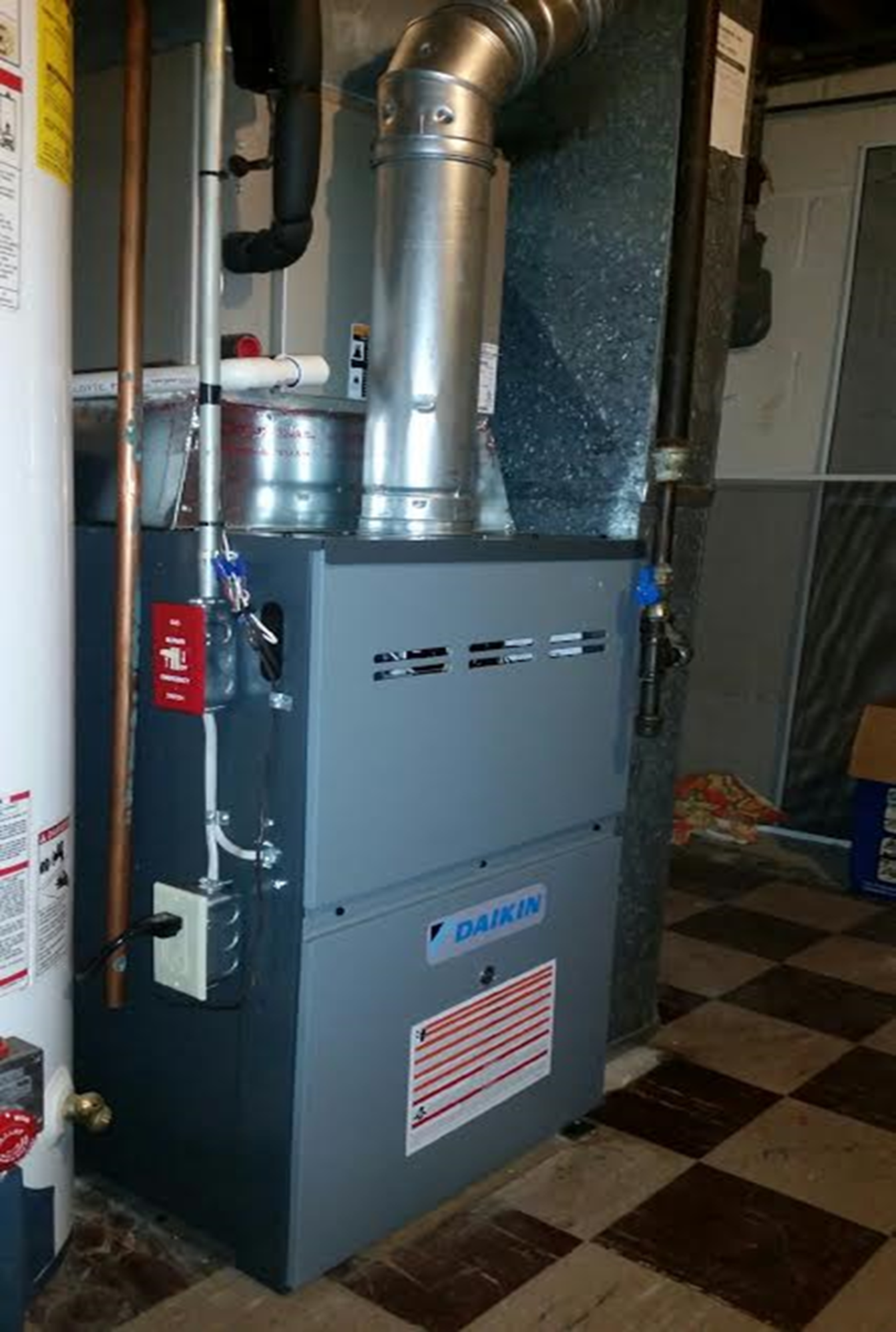 A gas heater is sitting in a room next to a water heater.