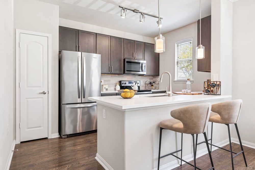Apartment kitchen with stainless steel appliances and a large island at Marquis at The Woodlands in Spring, TX.