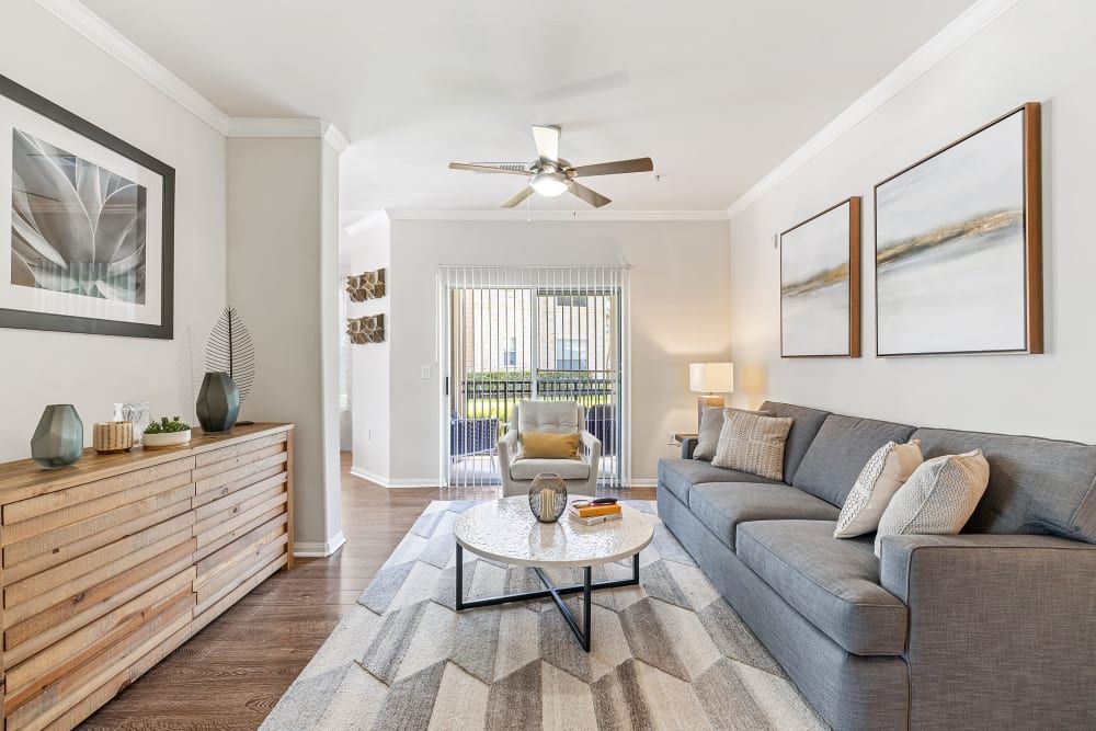 Modern living room with a couch, chair, coffee table, and ceiling fan at Marquis at The Woodlands in Spring, TX.