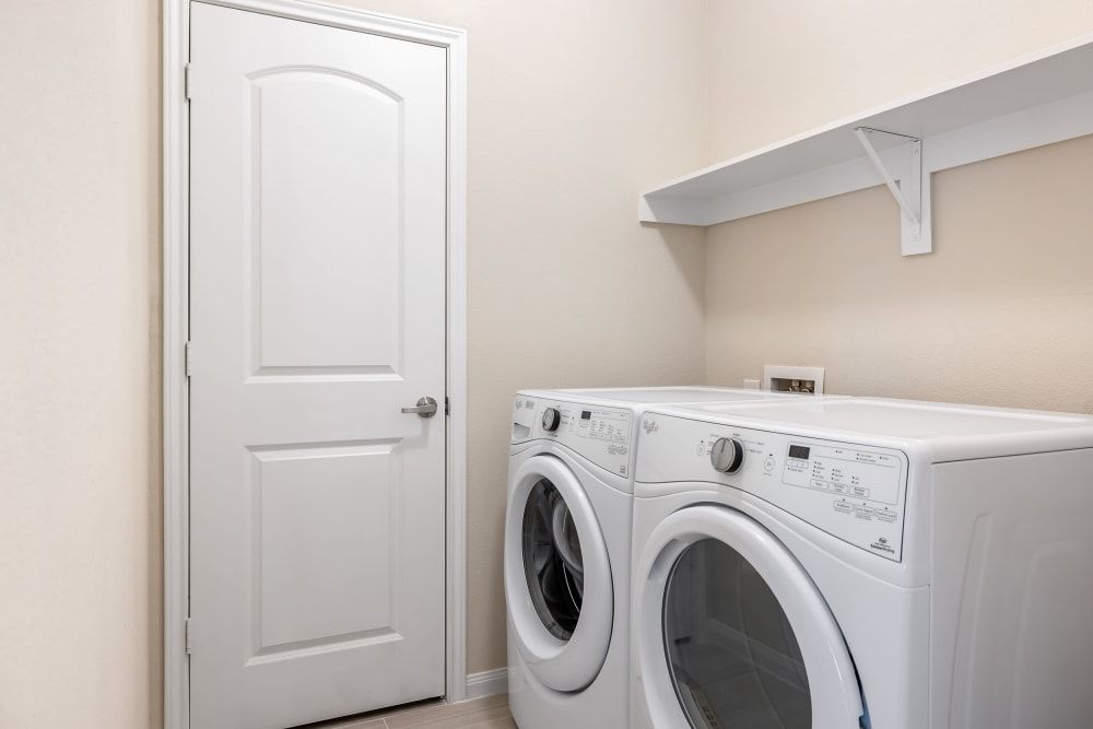 A laundry room with a washer and dryer and a door at Marquis at The Woodlands in Spring, TX.