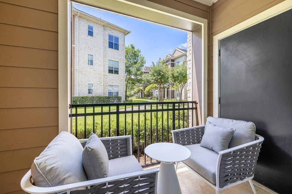 Spacious apartment balcony with couches and a table at Marquis at The Woodlands in Spring, TX.