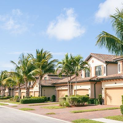 A row of houses with palm trees on the side of the road.