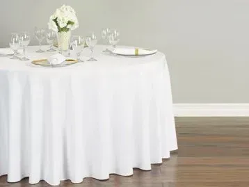 A round table with a white tablecloth and a vase of flowers on it.