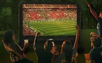 A group of people are watching a soccer game on a large screen.