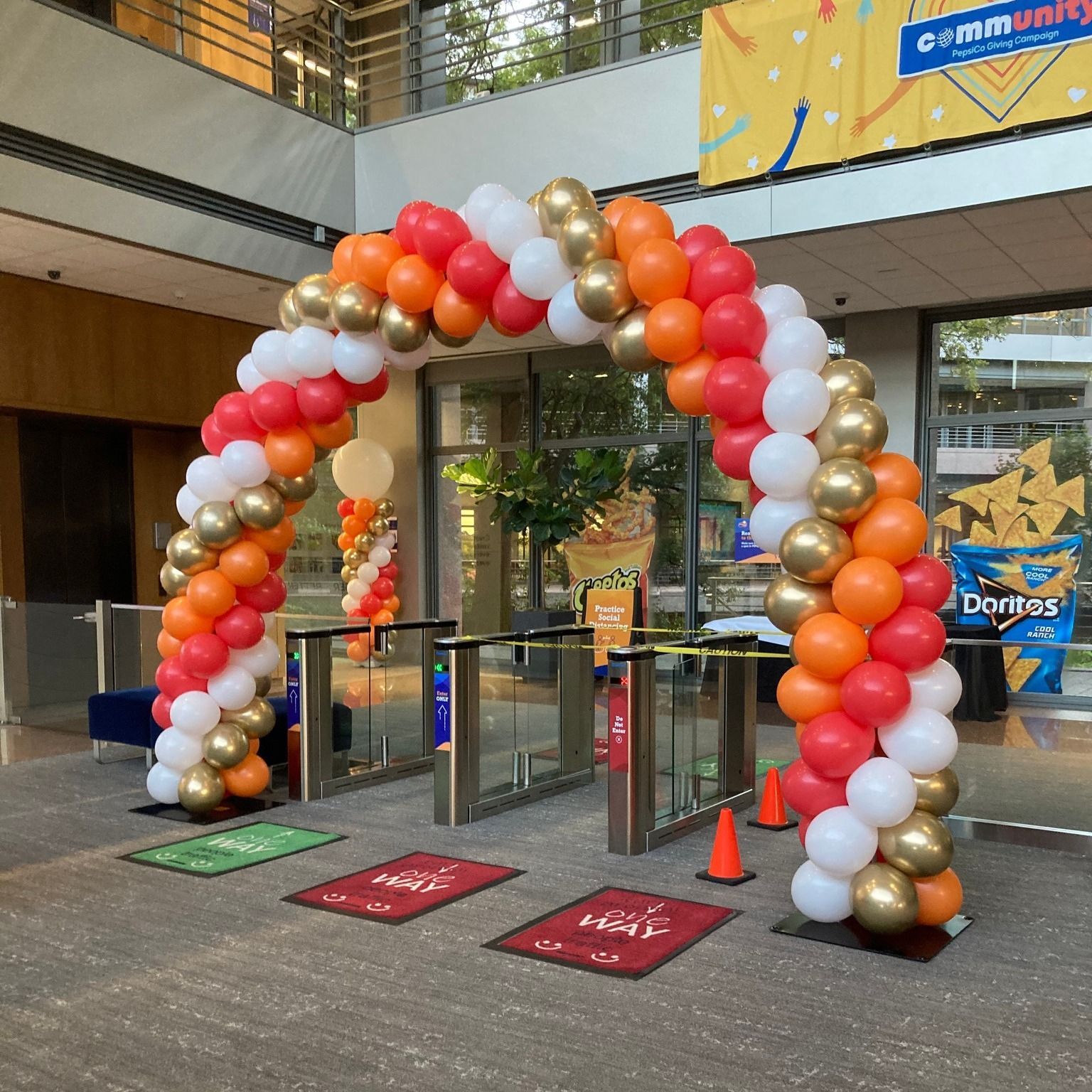 A red white and gold balloon arch in front of a building