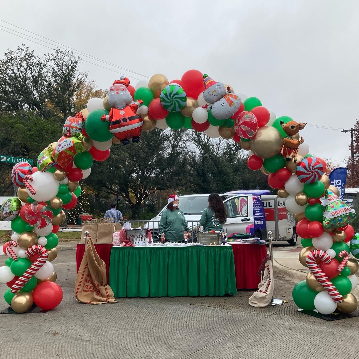 A woman is standing behind a table decorated with balloons and candy canes.
