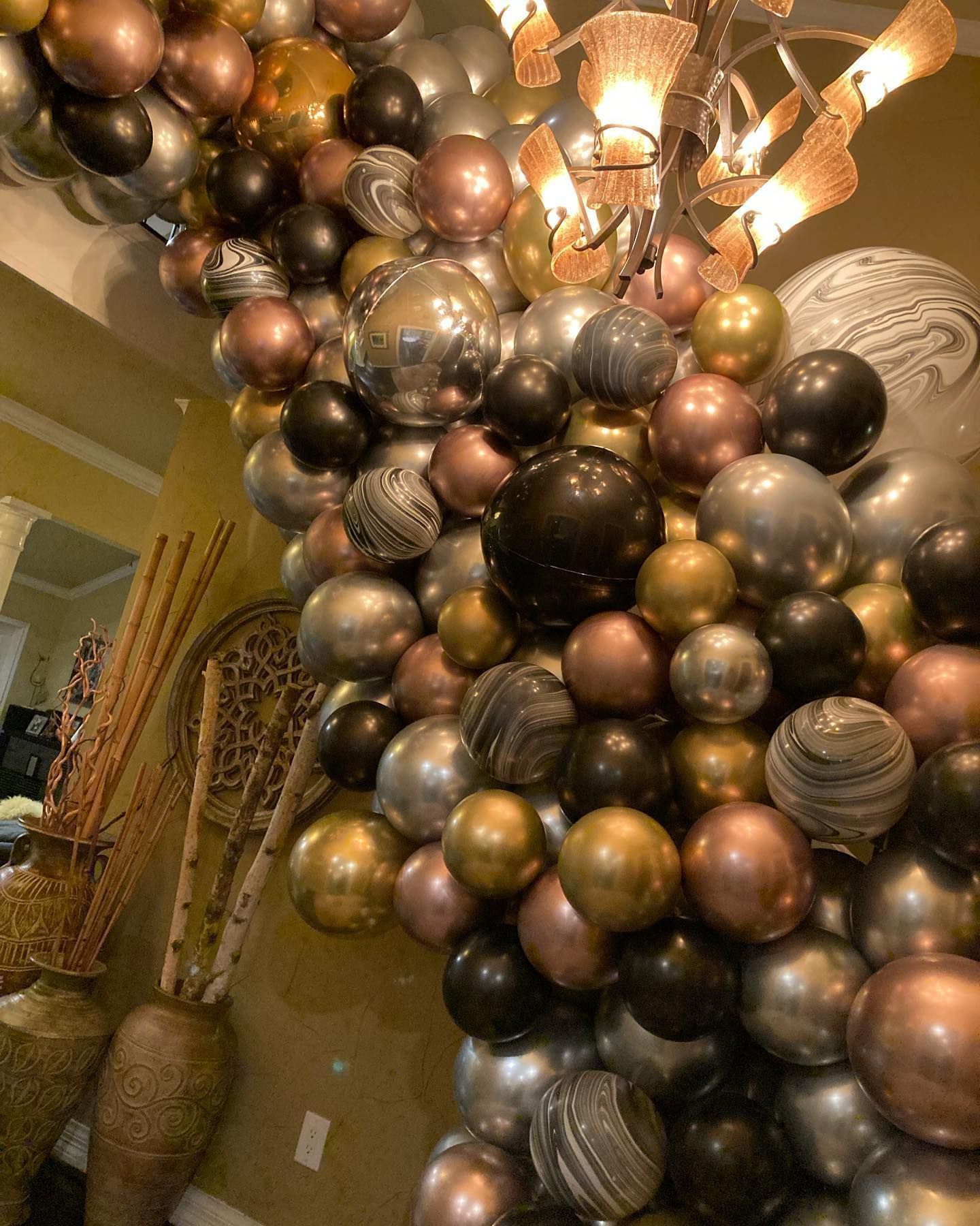 A bunch of balloons are hanging from a chandelier in a room.