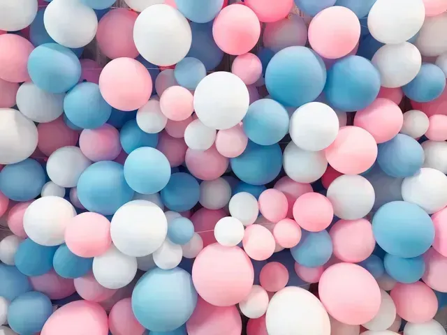 A bunch of pink and blue balloons are floating in the air.