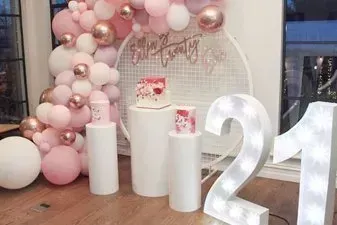 A room decorated with balloons and a cake for a 21st birthday.