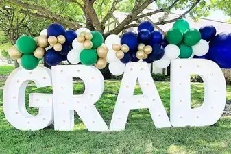 A large white sign that says `` grad '' is surrounded by balloons.