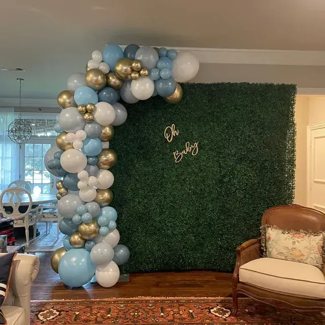 A room with balloons and a chair in front of a hedge wall.