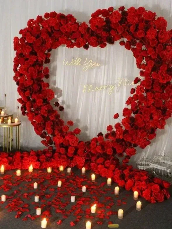 A heart shaped arch made of red roses and candles