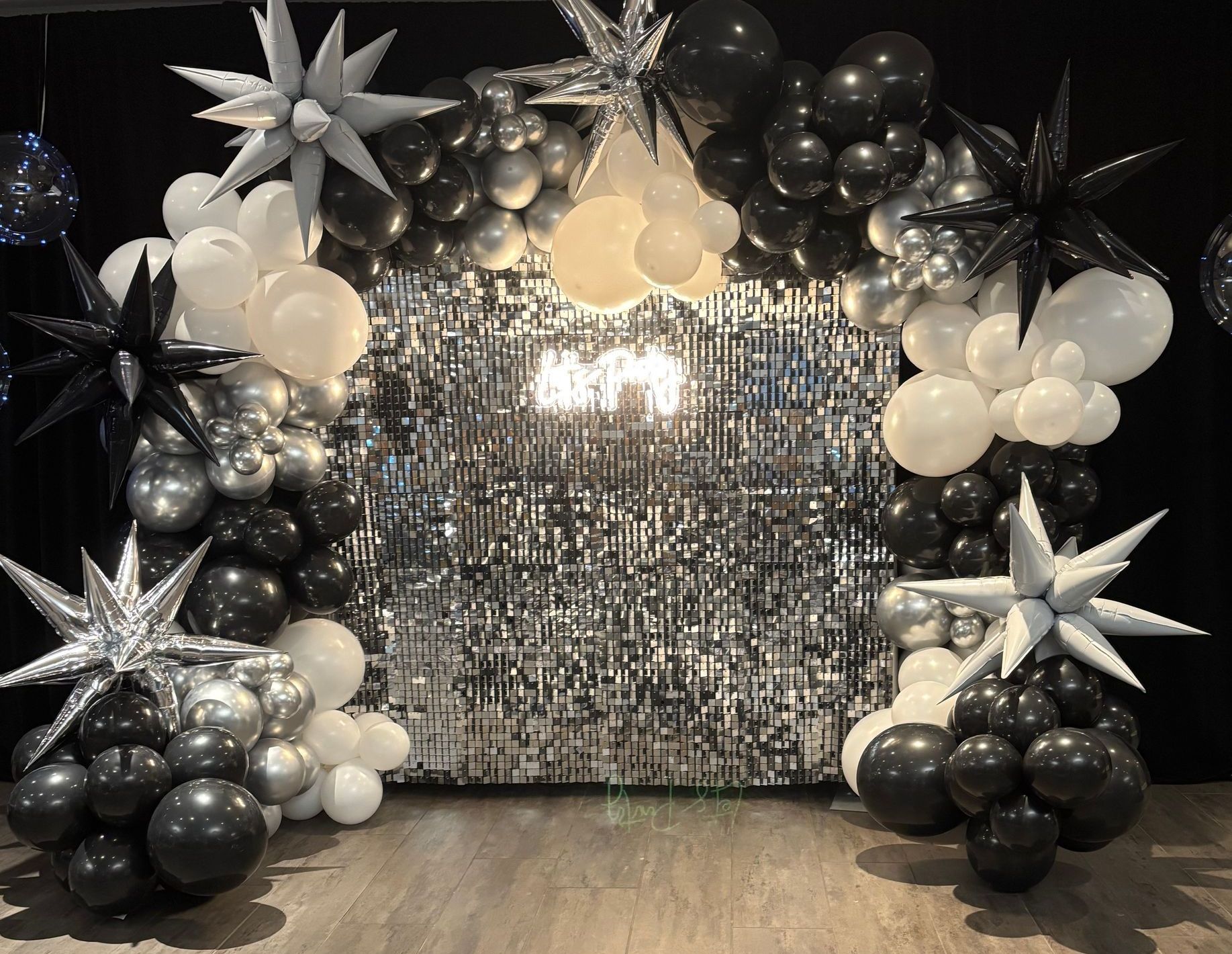 A wall covered in balloons and a neon sign that says `` twenty one ''.