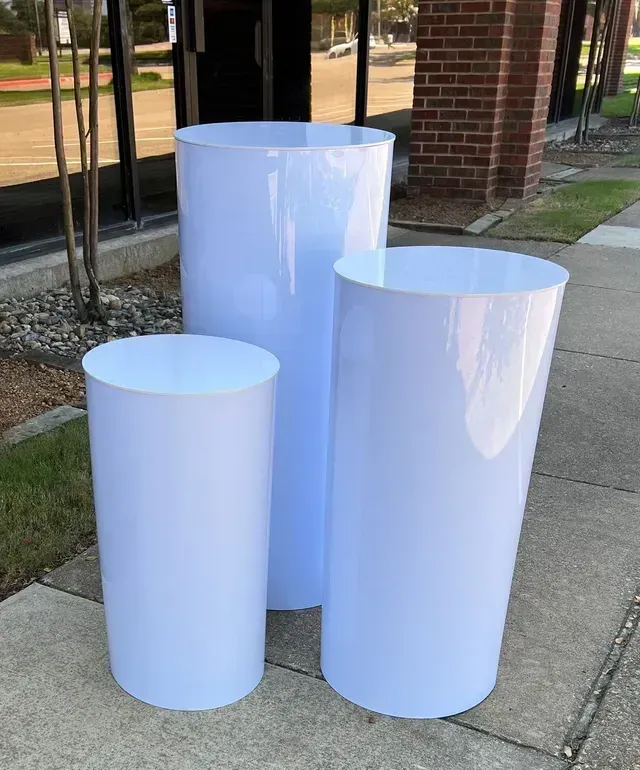 Three white cylinders are sitting on a sidewalk in front of a building.