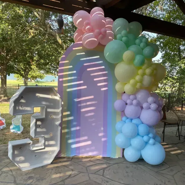 The number 3 is surrounded by balloons and a rainbow