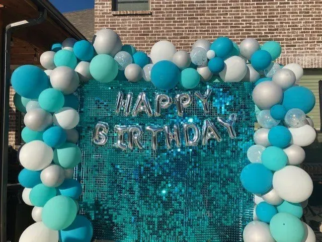 A happy birthday sign is surrounded by blue and silver balloons.