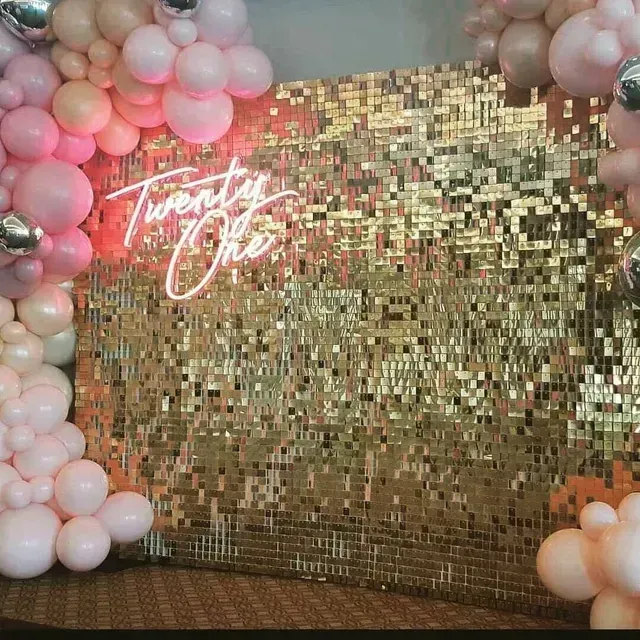 A wall covered in balloons and a neon sign that says `` twenty one ''.