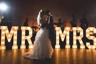 A bride and groom are dancing in front of a mr. and mrs. sign.