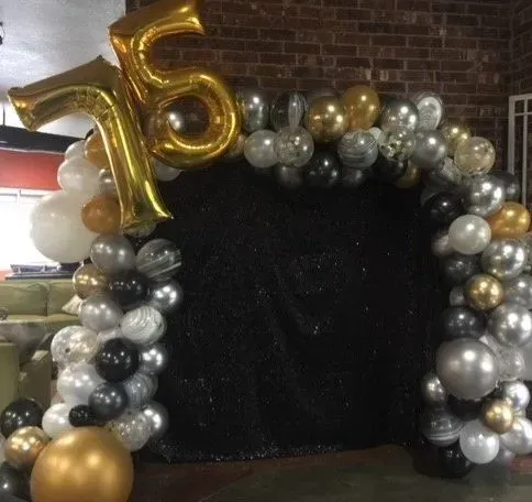 A bunch of balloons are sitting in front of a brick wall.