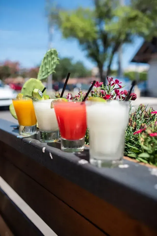 A row of drinks sitting on top of a wooden railing.