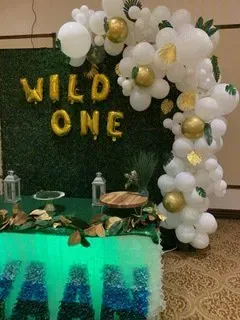 A table is decorated with balloons and a sign that says `` wild one ''.