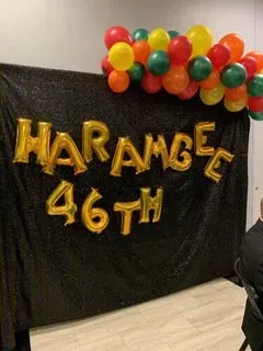 A person is standing in front of a sign that says harambe 46th.