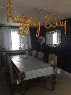 A dining room with a table and chairs and balloons hanging from the ceiling.