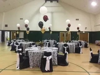 A large room filled with tables and chairs and balloons.