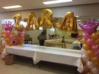 A room decorated with balloons and a table with the name zara on it.