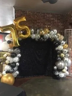 A bunch of balloons are sitting on a table in front of a brick wall.