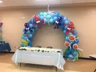 A table is decorated with balloons and a balloon arch.