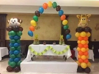 A table decorated with balloons and a monkey and a giraffe.