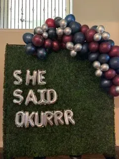 A wall with balloons on it that says `` she said okurrr ''.