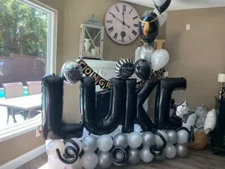 A room filled with balloons and a clock on the wall.