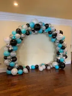 A bunch of balloons are sitting on a wooden floor in a room.