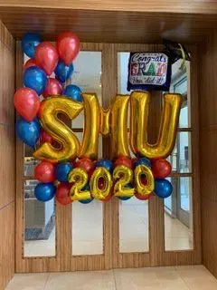A room decorated with gold , silver and black balloons for a 50th birthday.